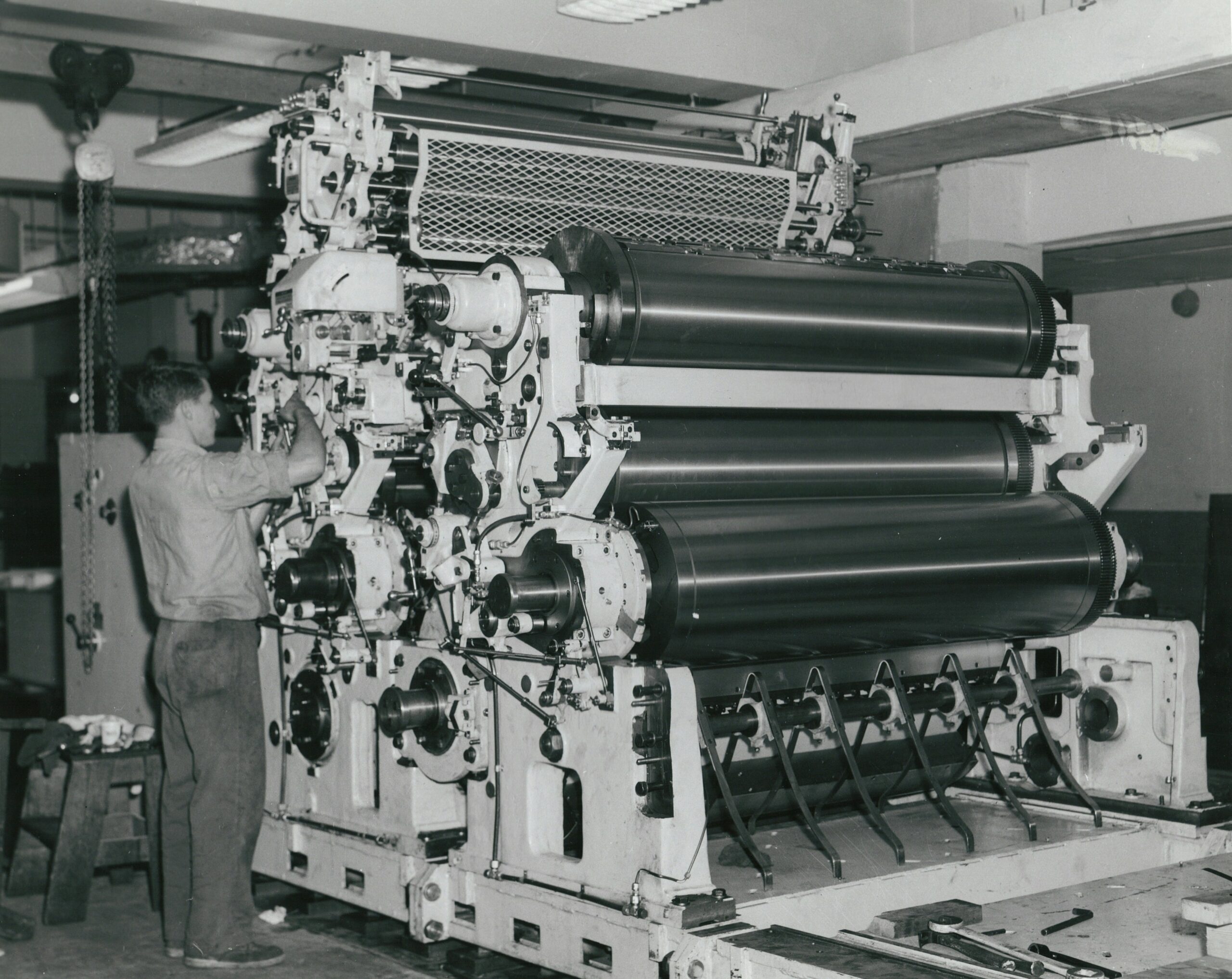 B&W photo of person standing at old printing press.